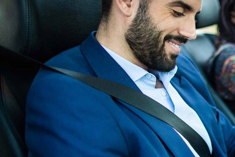 Man sitting in the passenger seat of a vehicle with his seatbelt on.